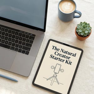 Könnte beinhalten: Ein Tablet mit dem Text The Natural Creator Starter Kit über einer Strichzeichnung eines Smartphones auf einem Stativ mit zwei Ringlichtern. Das Tablet liegt neben einem Laptop, einer blauen Keramiktasse mit Kaffee und einer kleinen Sukkulente.