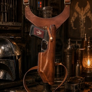 Peut inclure: Un holster d'épaule en cuir marron avec un pistolet assorti. Le holster a des sangles réglables et un design détaillé. Le pistolet porte un emblème rouge. L'arrière-plan comprend un casque et d'autres accessoires, suggérant un thème.