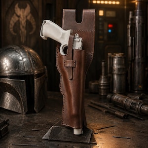 May include: A brown leather holster with a white pistol. The holster is designed to hold the pistol securely. The holster is displayed on a metal stand. The background includes a helmet and other props.