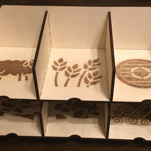 May include: A wooden organizer with six compartments, each with a different laser-engraved design. The designs include a sheep, wheat stalks, a shield, a building, a pile of rocks, and a tractor.
