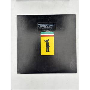 May include: A square black vinyl record sleeve featuring the text Jamiroquai Virtual Insanity and a serial number. Below the text is a rectangular graphic with green, white, and red stripes above a yellow field containing a black horned figure.