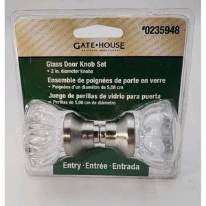May include: A glass door knob set with two clear, faceted knobs and a brushed nickel finish. The package indicates the knobs are 2 inches in diameter. The product is labeled "Gate House" and includes the text "Entry, Entrée, Entrada".