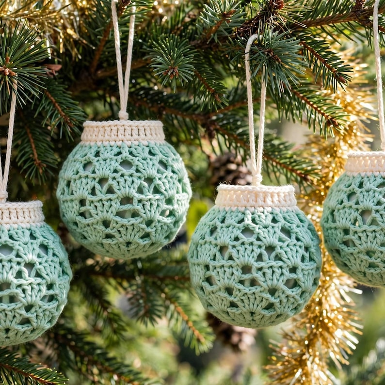Handmade mint green crocheted Christmas balls with openwork diamond lattice stitch hanging on a Christmas tree branch