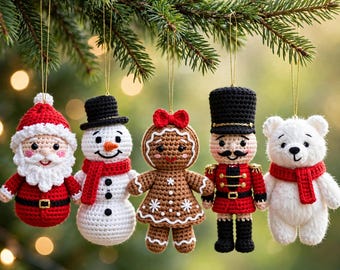 Op de afbeelding: Vijf gehaakte kerstornamenten hangend aan een dennentak: een kerstman, een sneeuwpop met een rode sjaal, een peperkoekfiguurtje met een rode strik, een notenkraker in een rood uniform en een witte ijsbeer met een rode sjaal.
