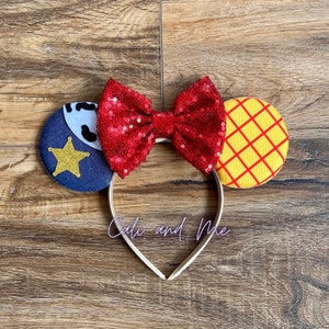 Peut inclure: Un serre-t&ecirc;te avec un n&oelig;ud rouge paillet&eacute;, une oreille en forme d'&eacute;toile de sh&eacute;rif bleu et blanc et une oreille &agrave; carreaux jaune et rouge. Le serre-t&ecirc;te dit "Cali and Me".