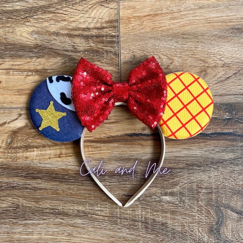 Peut inclure: Un serre-t&ecirc;te avec un n&oelig;ud rouge paillet&eacute;, une oreille en forme d'&eacute;toile de sh&eacute;rif bleu et blanc et une oreille &agrave; carreaux jaune et rouge. Le serre-t&ecirc;te dit "Cali and Me".
