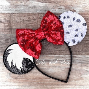 May include: A pair of black and white sequined Minnie Mouse ears with a red sequined bow. The ears are decorated with a Dalmatian spot pattern and a white furry tail.