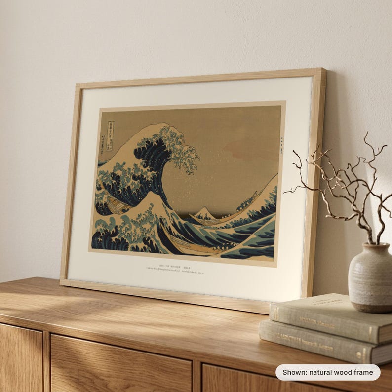 Hokusai's Great Wave in a natural wood frame leaning on a sideboard beside a vase of branches