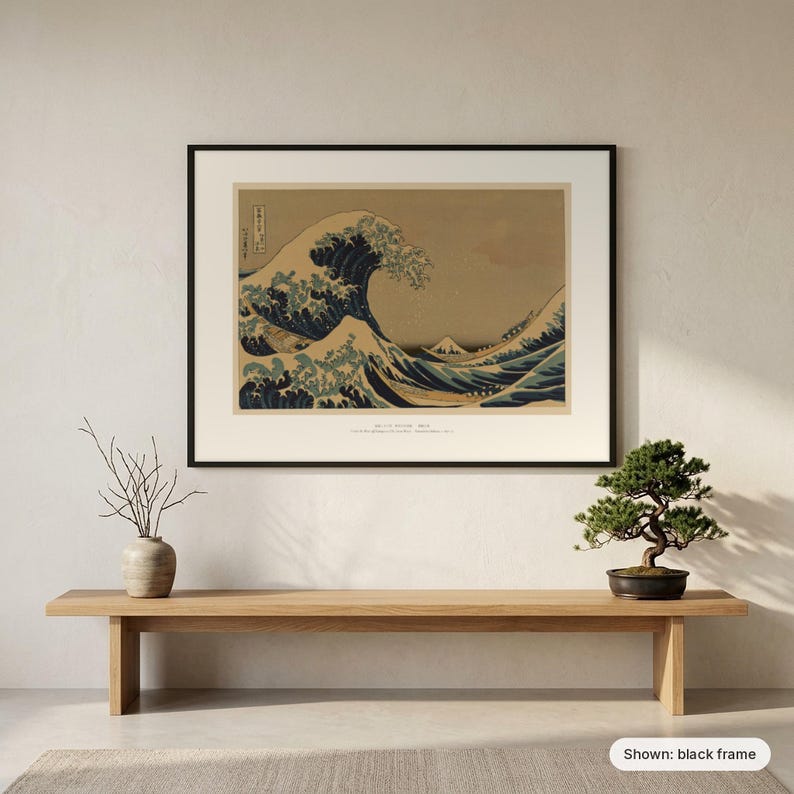 Hokusai's Great Wave in a black frame on a wall above a wooden bench with a bonsai