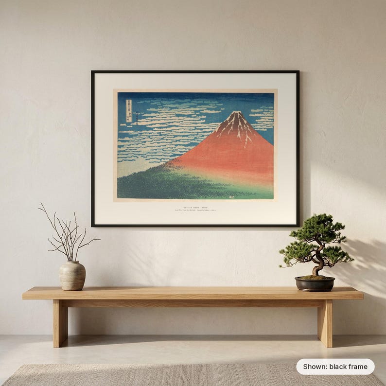 Hokusai's Red Fuji in a black frame on a wall above a wooden bench with a bonsai