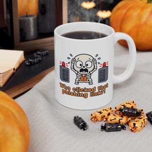 May include: A white ceramic mug featuring a cartoon skeleton with an orange IT badge, holding its head in distress between two server towers with red lights. The text reads, Who clicked that phishing link?! The mug is filled with a dark liquid.