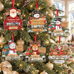 May include: Six personalized acrylic Christmas ornaments hanging on a tree. Designs include Santa, snowmen, and a reindeer with text like Christmas Cash for Brighter Days, Believe in the Magic, and Good Things Ahead, featuring slots for rolled cash.