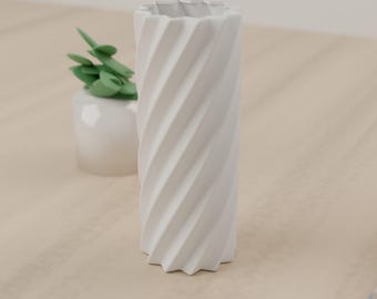 May include: A white cylindrical vase featuring a distinct spiral or twisted geometric pattern along its exterior surface. The vase has a scalloped top edge and a matching scalloped base, creating a uniform, repeating vertical texture.