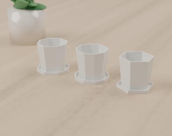 May include: Three white, octagonal-shaped planters, each featuring a matching integrated saucer base. The planters have a clean, geometric design with flat vertical panels and an open top, arranged in a row on a light-colored surface.