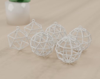 May include: A set of five white geometric ornaments, each featuring a hollow, multi-faceted, cage-like structure with a small loop at the top for hanging. The objects are arranged in a cluster, showcasing their intricate, interconnected frame design.