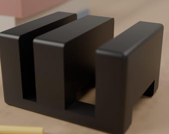 May include: A matte black desk organizer featuring three vertical slots for holding items. The rectangular block has a solid base and clean, straight edges, providing a stable structure for organizing various small objects on a flat surface.