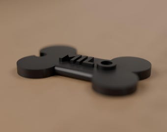 May include: A matte black pet tag shaped like a bone with the name MILO embossed in raised lettering on the top surface. The tag features a circular hole on the right side for attachment, presenting a clean and solid construction.