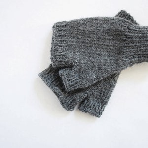 May include: Gray fingerless gloves made of knitted wool.