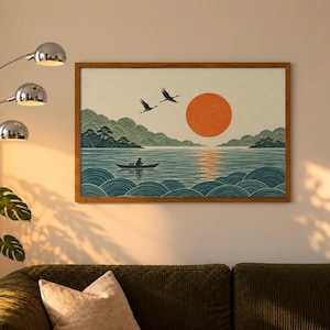 May include: A rectangular wall art print in a wooden frame featuring a landscape illustration of a calm lake with stylized blue waves, a small boat with a person rowing, two flying cranes, and a large orange sun against a cream background.