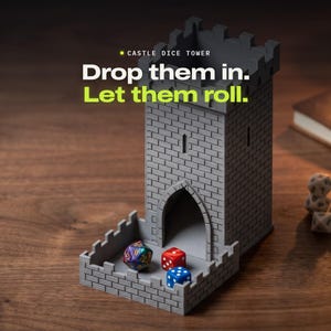 Może przedstawiać: Szara wieża na kości w kształcie zamku z wzorem cegieł, zawierająca tekst "CASTLE DICE TOWER" oraz "Drop them in. Let them roll.". Trzy wielościenne kości w kolorze fioletowym, czerwonym i niebieskim leżą u podstawy, z dodatkowymi kośćmi obok.