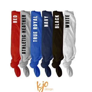 May include: A display of six folded t-shirts in various colors: red, athletic heather, true royal, navy, black, and white. Each shirt has its color name printed vertically in white. The image includes a small, orange logo in the bottom corner.