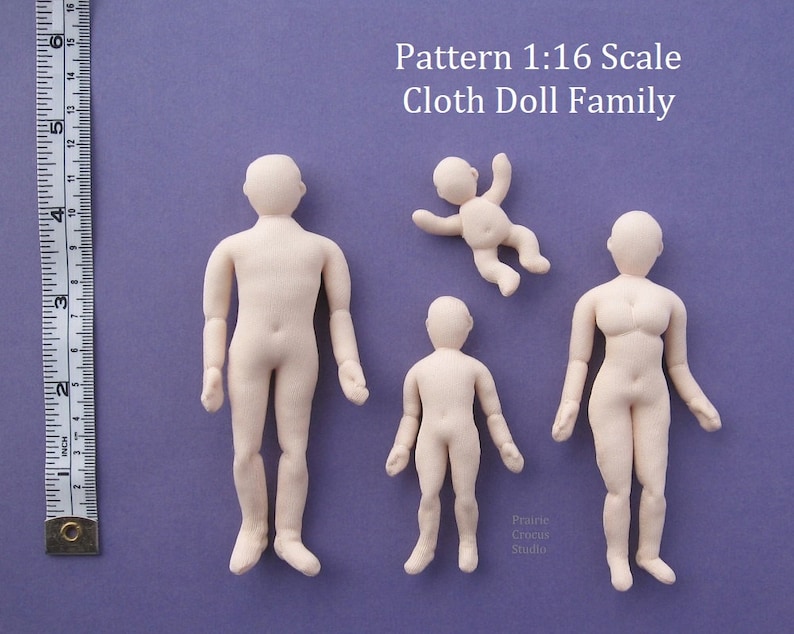 May include: A set of four unpainted cloth doll figures in various sizes, including a baby, a child, and two adults. The dolls are made of a soft, beige fabric and are ready to be customised with paint, fabric, and accessories. The dolls are arranged on a purple background with a ruler for scale. The text "Pattern 1:16 Scale Cloth Doll Family" is visible at the top of the image.
