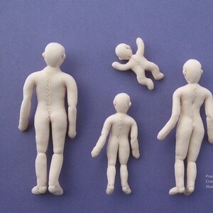 May include: Four handmade fabric dolls of varying sizes, all with a light beige colour. The dolls are standing on a purple surface. The dolls are all in different poses, with one doll lying on its back.