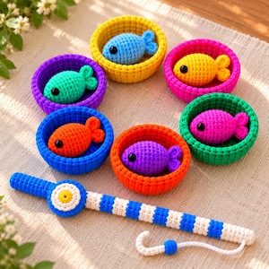 May include: A set of six crocheted bowls in yellow, pink, green, orange, blue, and purple, each containing a matching crocheted fish with black bead eyes. A long, striped blue and white crocheted fishing rod with a hook is positioned below.