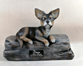 May include: A ceramic dog memorial statue. The dog is black and tan, lying on a stone-like base. A plaque on the base reads "Diego" with dates and the phrase "forever loved never forgotten."