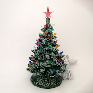 Könnte beinhalten: Ein grüner Keramik-Weihnachtsbaum mit einem roten Stern oben und bunten Lichtern. Der Baum ist beleuchtet und hat ein weißes Kabel.