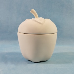 May include: White ceramic apple-shaped container with a lid. The lid has a leaf design on top.