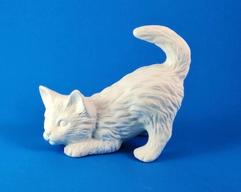 May include: White ceramic figurine of a cat in a playful pose, with its tail curled up and its head tilted down. The cat is sculpted with realistic fur details.