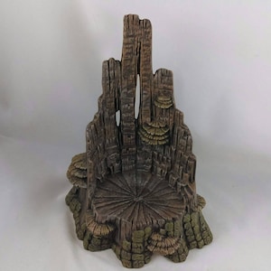 May include: A decorative, miniature tree stump chair with a carved design. The chair is primarily brown with green and tan accents, featuring a circular seat and a textured back resembling a tree trunk. The chair is designed to look like a miniature throne.