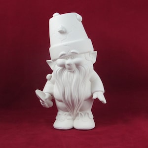 May include: A white ceramic gnome figure with a long beard and a tall hat. The gnome is holding a small object and has a cheerful expression. The figurine is unpainted and ready for painting or other decoration.