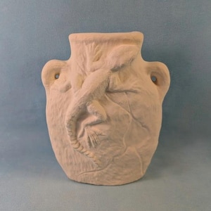 Peut inclure: Un vase en céramique blanc cassé mat présentant un relief sculpté d'un lézard rampant sur la surface avant. Le récipient possède une large ouverture, un corps arrondi et deux petites anses latérales avec des ouvertures circulaires intégrées.