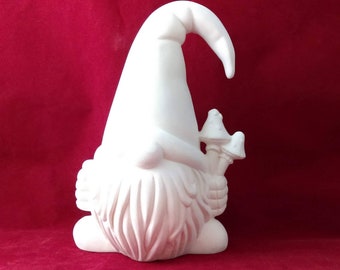 Może przedstawiać: Biała ceramiczna figurka gnoma z czapką z daszkiem i brodą. Gnom trzyma w ręku dwa grzyby.
