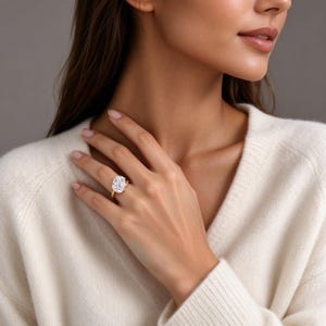 Puede incluir: Un anillo de oro con una gran piedra preciosa transparente de forma ovalada y tallada, montada en un engaste de garras. La banda es de oro fino y pulido, con un diseño clásico que resalta el brillo de la piedra central.
