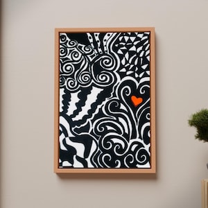 May include: A rectangular wall art piece in a light wood frame featuring a high-contrast black and white abstract pattern of swirls, waves, and geometric shapes, accented by a single small, solid orange heart near the center right.