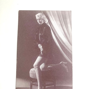 vintage pinup female photo ephemera card with woman standing pointing down her leg