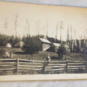 antique photo of a man sitting on a fence