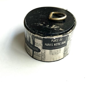 vintage cardboard oval box with black and white french image motifs on side and metal circle handle on top
