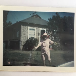 vintage color photo of woman standing with a running garden hose