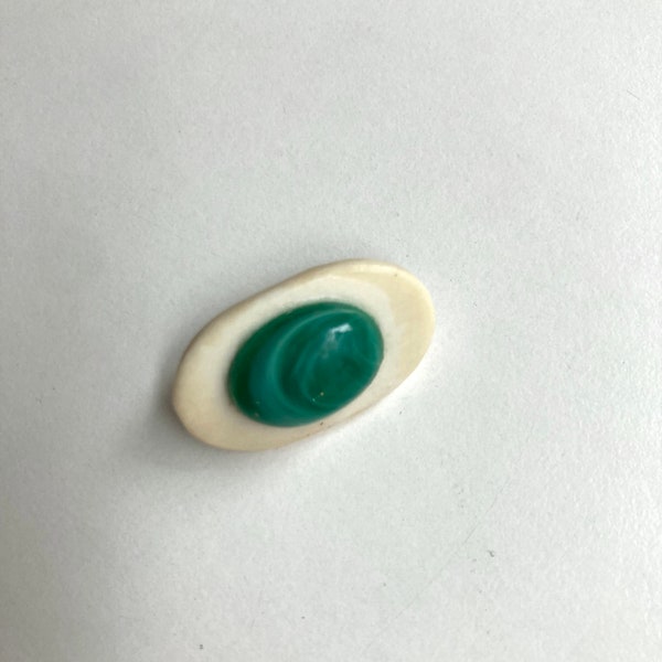 vintage little brooch of carved bone with a green gem in center
