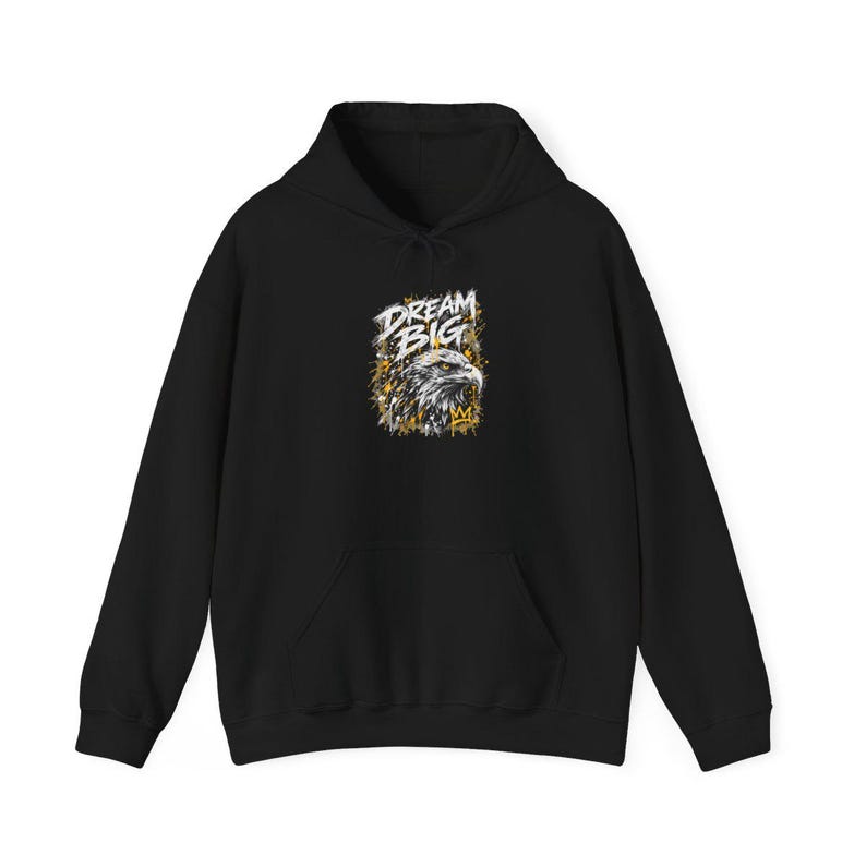 K&ouml;nnte beinhalten: Ein schwarzer Kapuzenpullover mit einer Grafik auf der Brust. Das Design zeigt einen detaillierten Adlerkopf in Wei&szlig;- und Graut&ouml;nen, begleitet vom Schriftzug "DREAM BIG" in wei&szlig;en Buchstaben und gelben Farbspritzern.