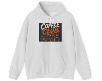 Peut inclure: Un sweat à capuche gris chiné clair arborant un motif rectangulaire central avec le texte COFFEE CLUB en crème et orange. Le design comprend des illustrations de grains de café, une branche de caféier et une tasse de café fumante.