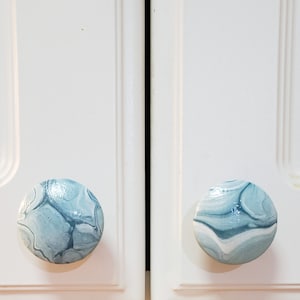 May include: Two blue and white marbled cabinet knobs with a glossy finish.