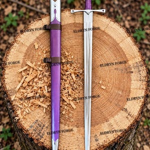 Op de afbeelding: Een metalen zwaard met een zilverkleurig lemmet, een kruisvormige pareerstang en een paars omwikkeld handvat, vergezeld van een bijpassende paarse schede met zilveren metalen accenten en bruine lederen riemen, gemarkeerd met ELDRYN FORGE.