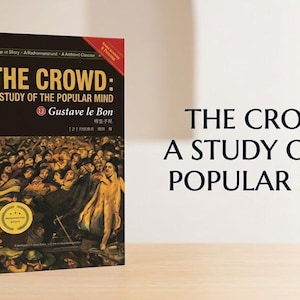 May include: A paperback book titled The Crowd: A Study of the Popular Mind by Gustave le Bon. The black cover features a historical painting of a dense crowd and a gold circular seal. The title is printed in large yellow and white text.