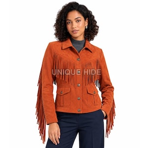 May include: A rust-colored suede jacket featuring long fringe detailing across the chest and down the sleeves. The jacket includes a button-up front, two front flap pockets, and a collar. The text UNIQUE HIDE is visible on the front.
