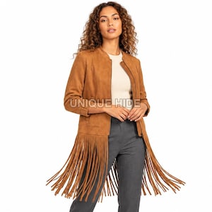 Puede incluir: Una chaqueta de ante color tostado con cuello redondo, cierre de cremallera frontal y largos flecos a lo largo del dobladillo. La prenda se lleva sobre un top color crema y pantalones grises. El texto UNIQUE HIDE es visible.